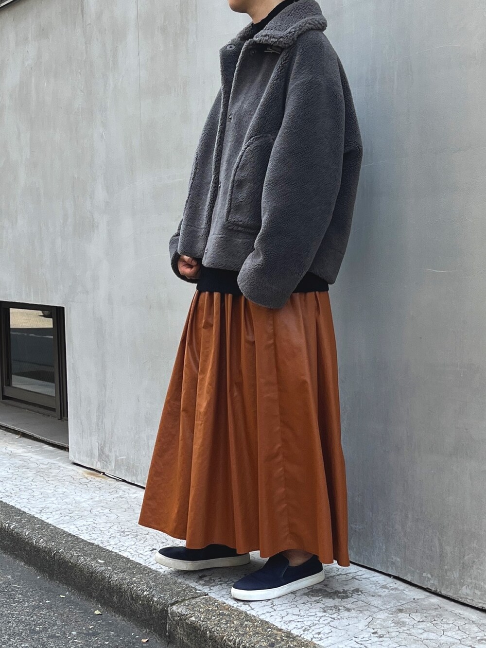 グレー系のムートンコート、レッド系のスカート、ブラック系のTシャツ/カットソーを着用したレディースの秋コーディネートの2枚目の写真