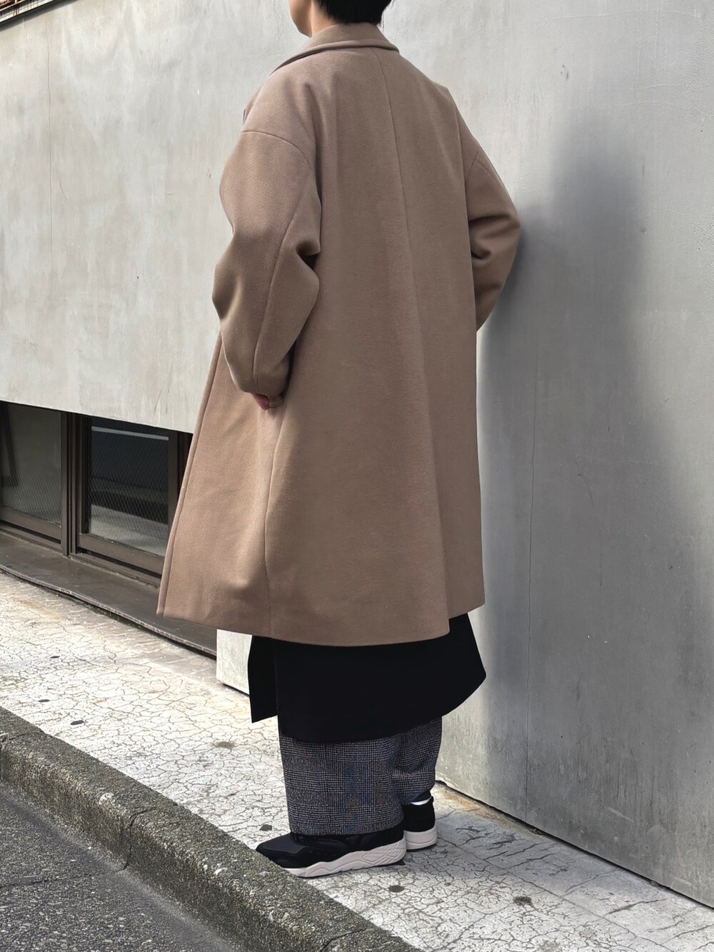 ブラウン系のチェスターコート、ブラック系のワンピース、ブラック系のその他パンツを着用したレディースの冬コーディネートの2枚目の写真