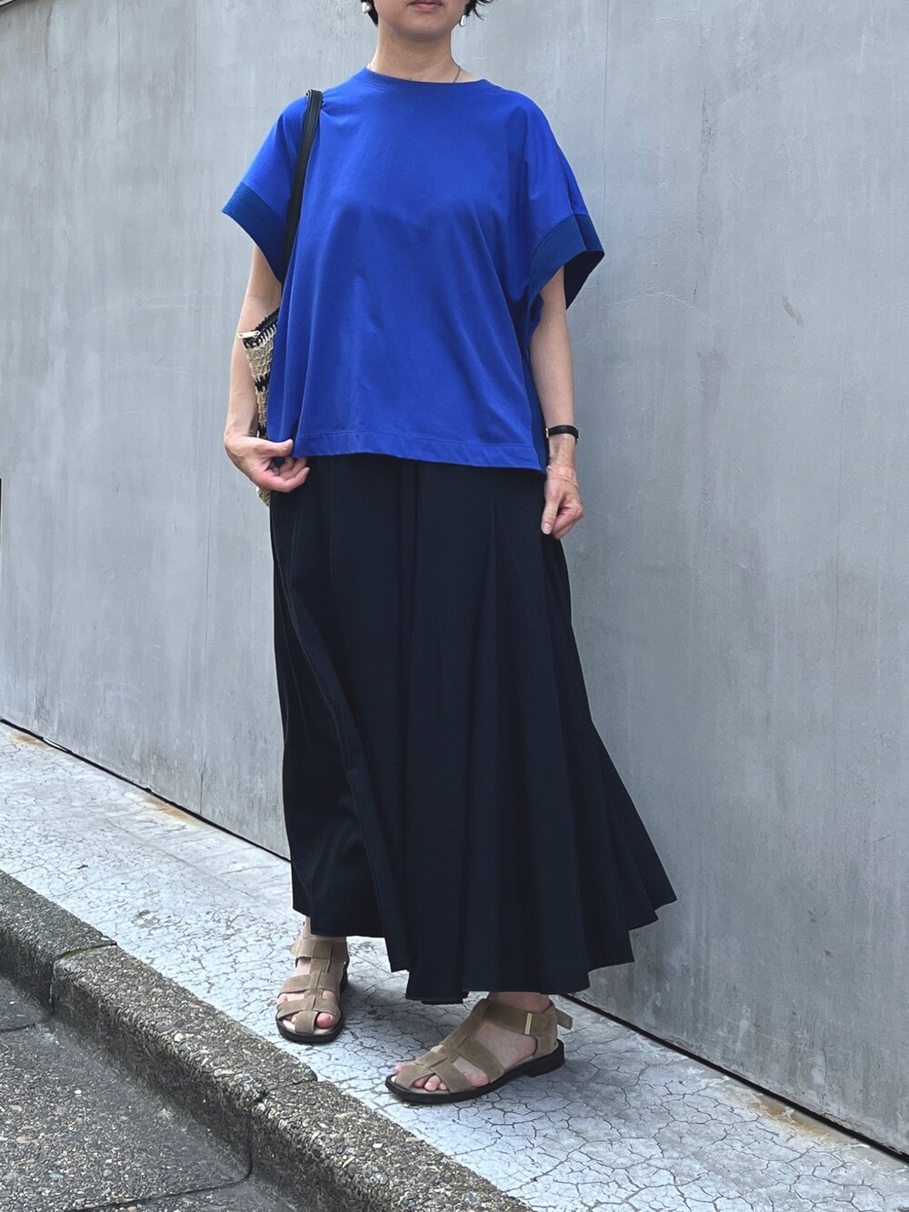 ブルー系のTシャツ/カットソー、ブラック系のデニムスカート、ブラック系のかごバッグを着用したレディースの夏コーディネートの2枚目の写真