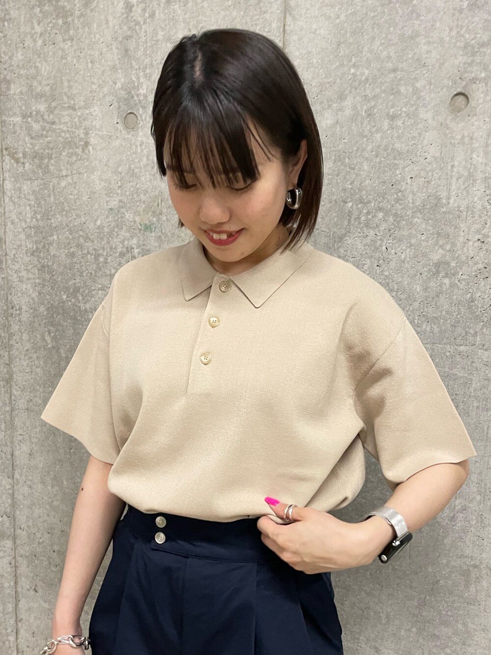 ブラック系のスカート、ブラック系のショルダーバッグ、ベージュ系のポロシャツを着用したレディースの春コーディネートの4枚目の写真