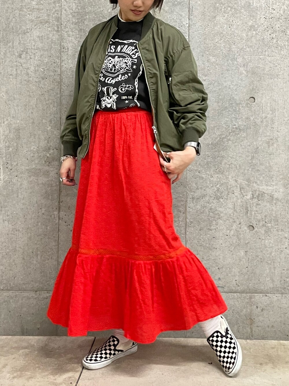 グレー系のTシャツ/カットソー、レッド系のスカート、グリーン系のブルゾンを着用したレディースの春コーディネートの4枚目の写真