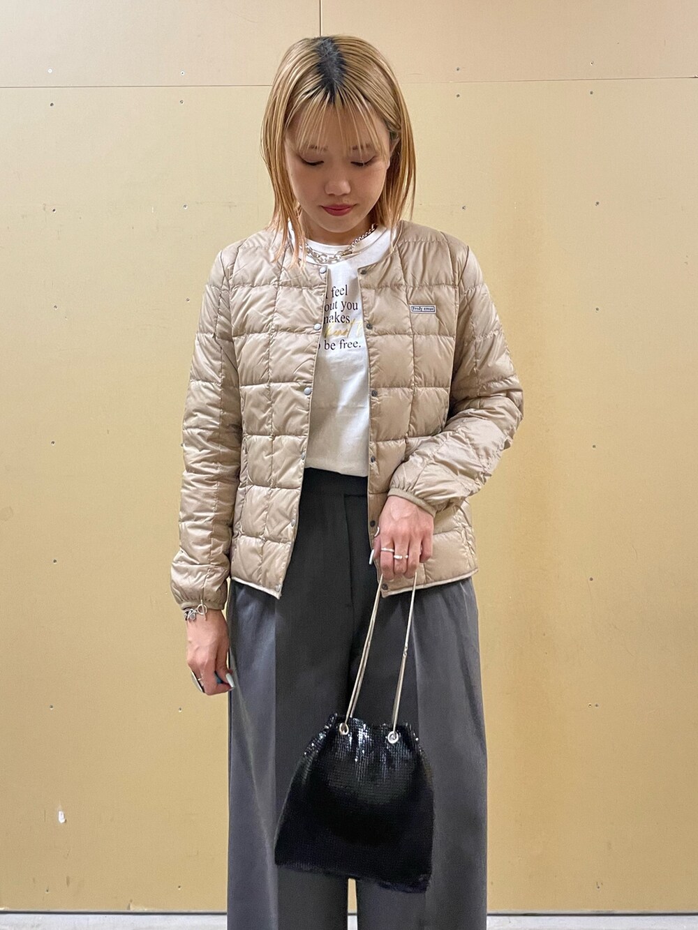 ホワイト系のTシャツ/カットソー、ベージュ系のダウンジャケット/コート、グレー系のその他パンツを着用したレディースの秋コーディネートの4枚目の写真