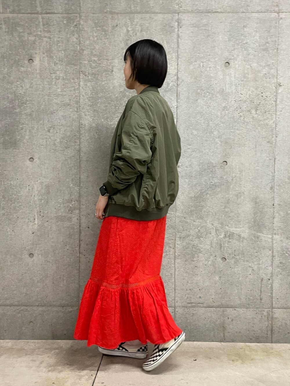 グレー系のTシャツ/カットソー、レッド系のスカート、グリーン系のブルゾンを着用したレディースの春コーディネートの2枚目の写真