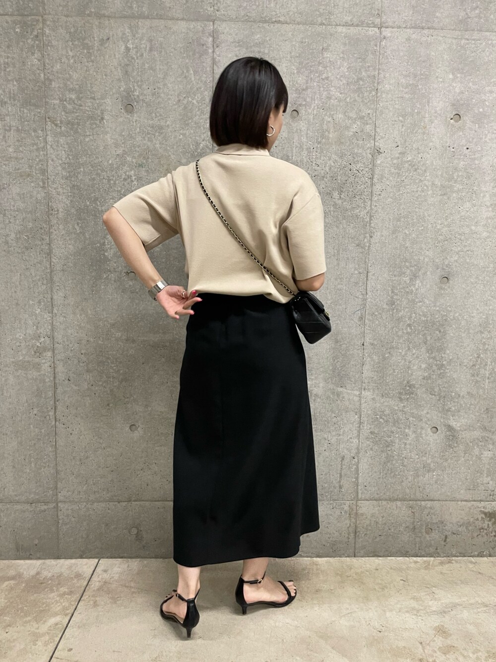 ブラック系のスカート、ブラック系のショルダーバッグ、ベージュ系のポロシャツを着用したレディースの春コーディネートの3枚目の写真