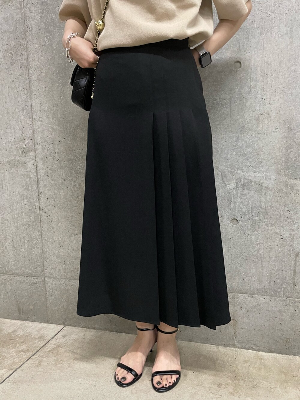 ブラック系のスカート、ブラック系のショルダーバッグ、ベージュ系のポロシャツを着用したレディースの春コーディネートの5枚目の写真