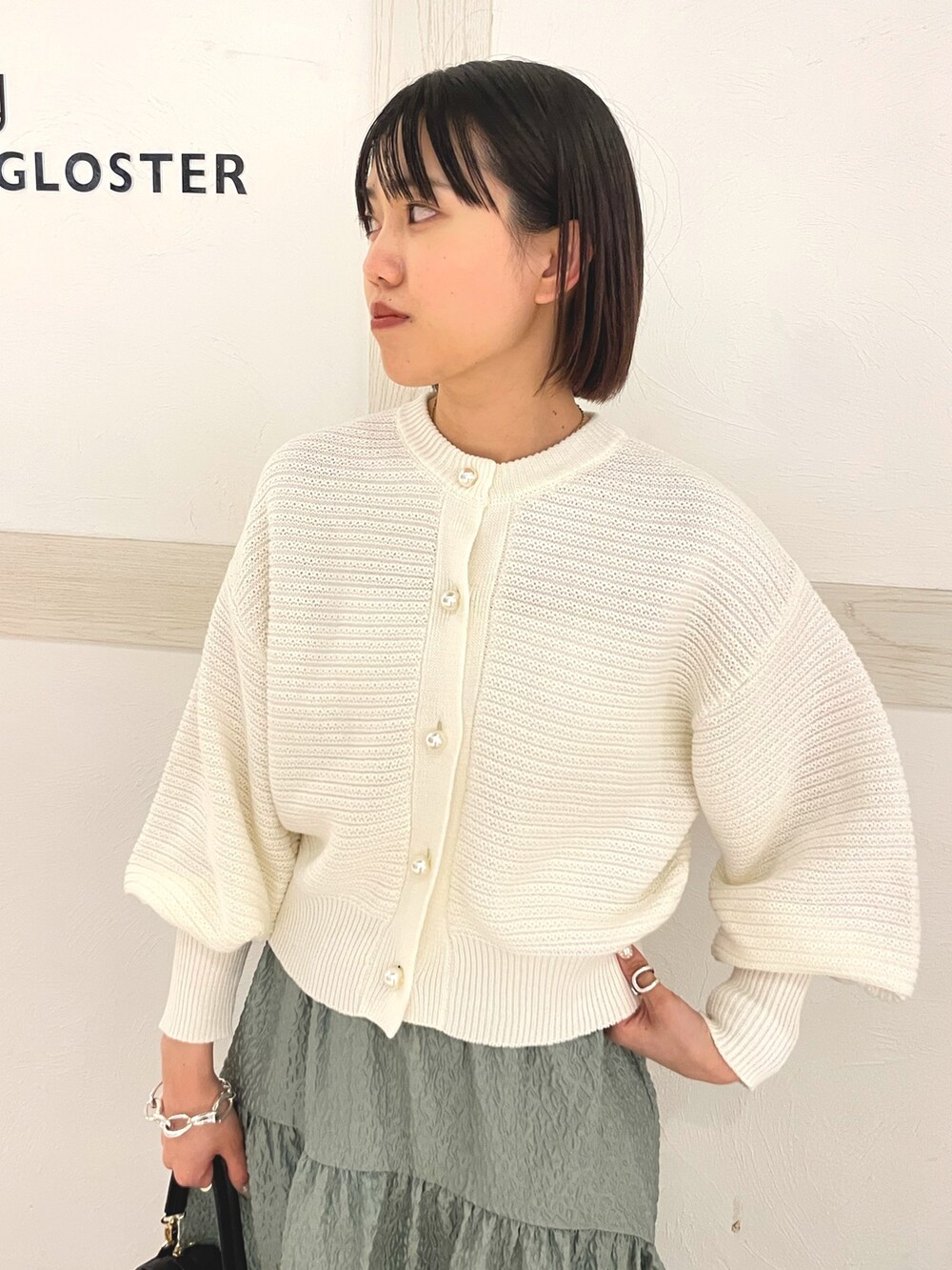 ホワイト系のカーディガン/ボレロ、ホワイト系のショルダーバッグ、グリーン系のスカートを着用したレディースの春コーディネートの4枚目の写真