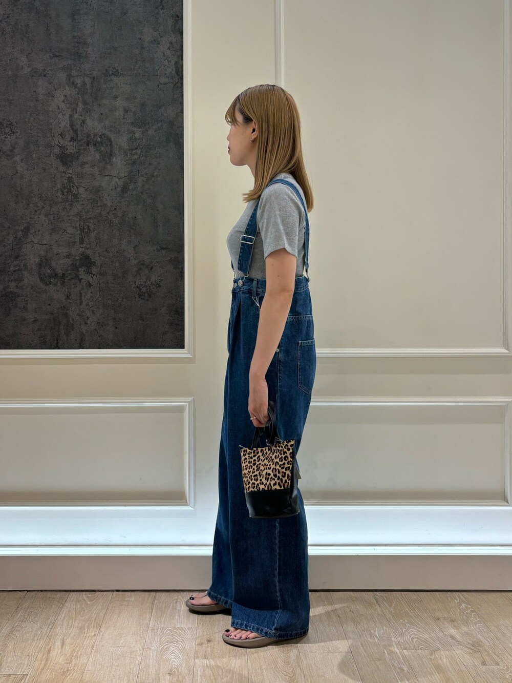 ブルー系のデニムパンツ、ブラック系のサンダル、ベージュ系のショルダーバッグを着用したレディースの夏コーディネートの3枚目の写真