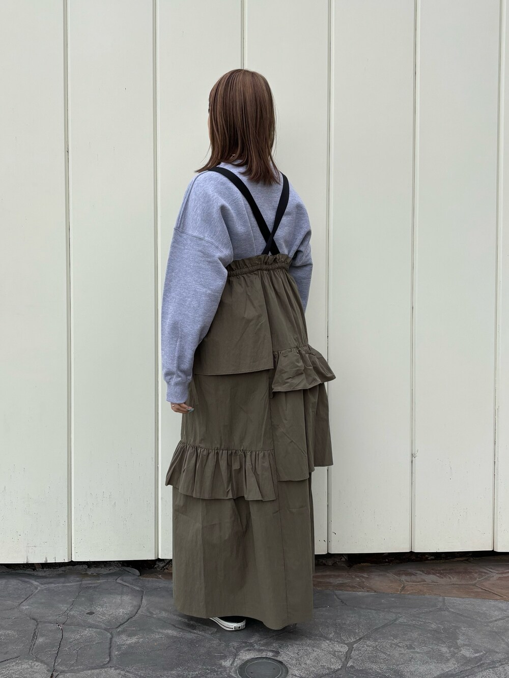 グリーン系のジャンパースカート、グレー系のスウェット、ブルー系のショルダーバッグを着用したレディースの冬コーディネートの3枚目の写真