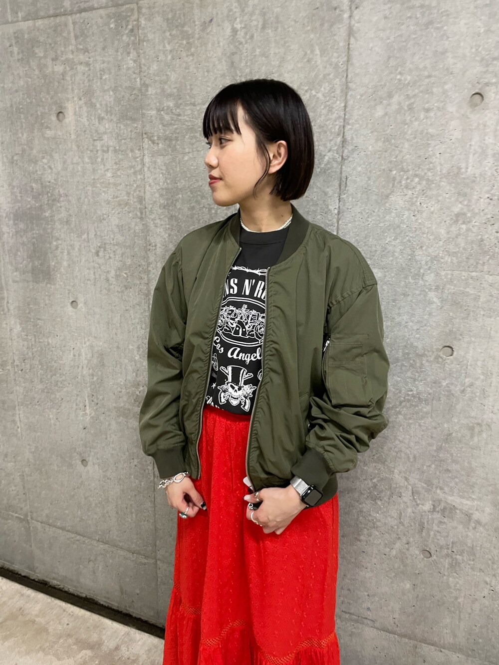 グレー系のTシャツ/カットソー、レッド系のスカート、グリーン系のブルゾンを着用したレディースの春コーディネートの5枚目の写真