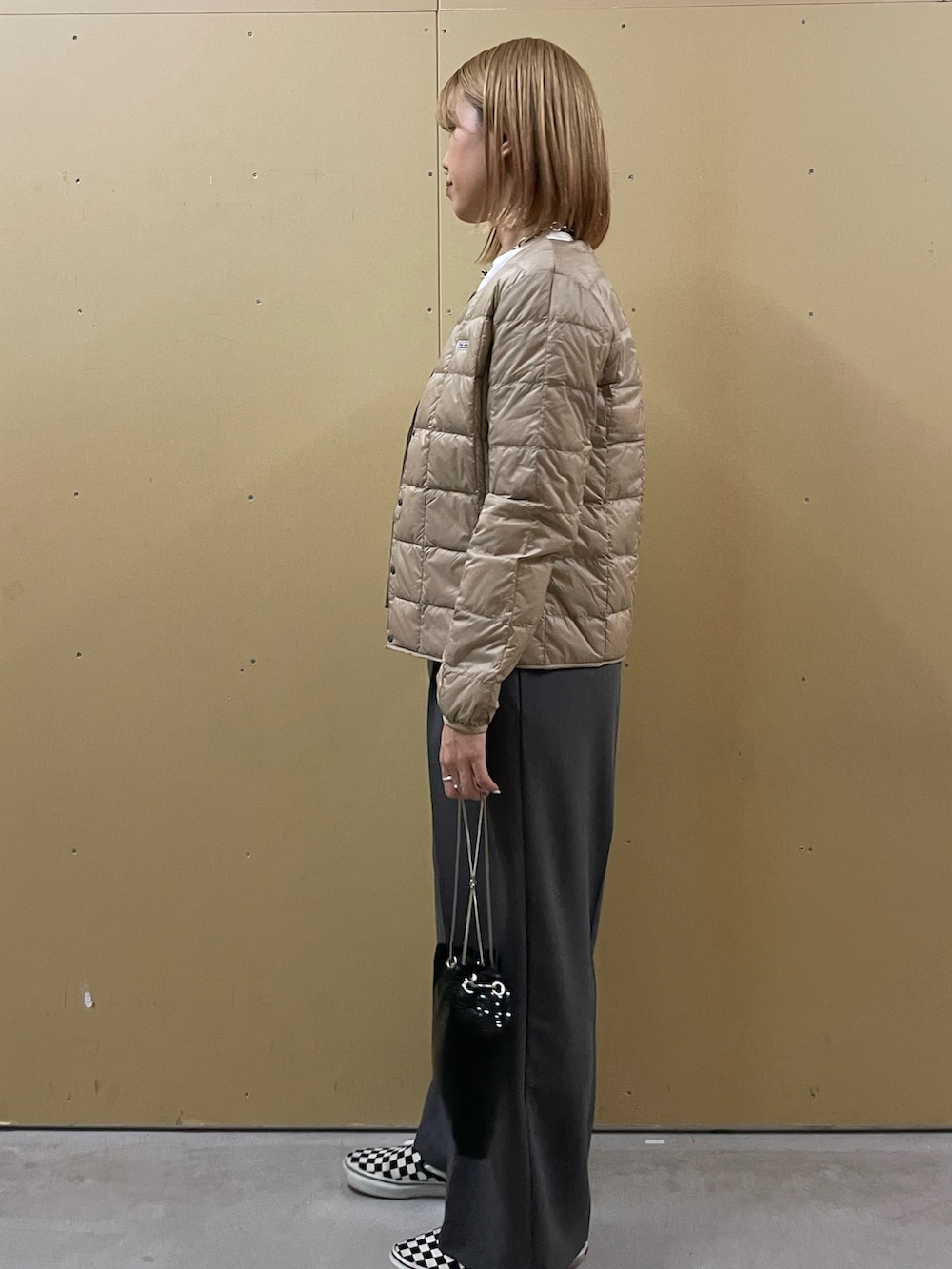 ホワイト系のTシャツ/カットソー、ベージュ系のダウンジャケット/コート、グレー系のその他パンツを着用したレディースの秋コーディネートの2枚目の写真