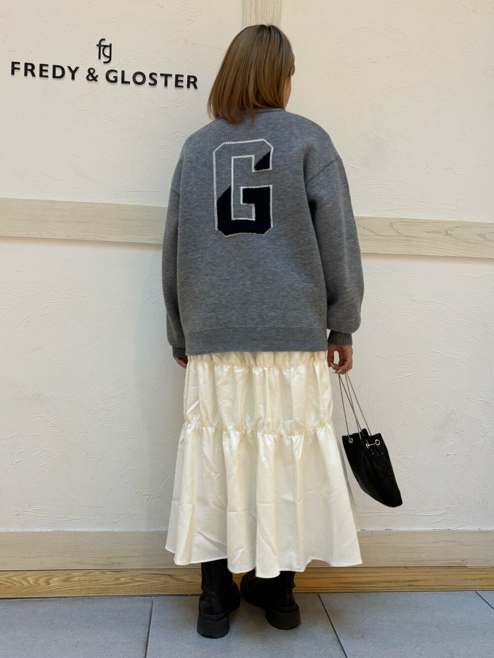 ブラック系のショルダーバッグ、イエロー系のスカート、ブルー系のニット/セーターを着用したレディースの冬コーディネートの3枚目の写真