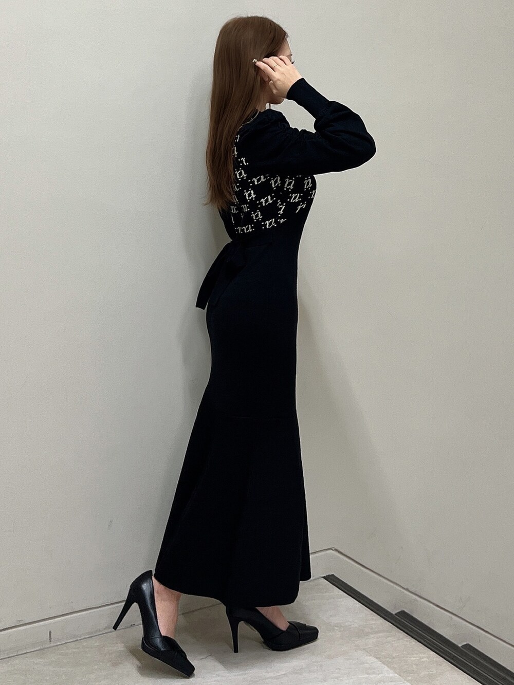 ブラック系のワンピース、ブラック系のショルダーバッグ、ブラック系のパンプスを着用したレディースの冬コーディネートの3枚目の写真