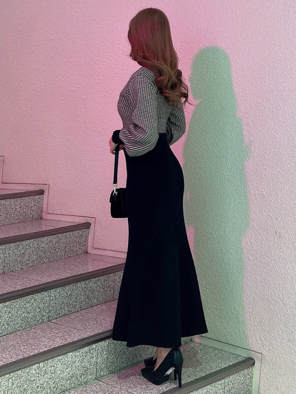 ブラック系のワンピース、ブラック系のパンプス、ブラック系のショルダーバッグを着用したレディースの冬コーディネートの4枚目の写真