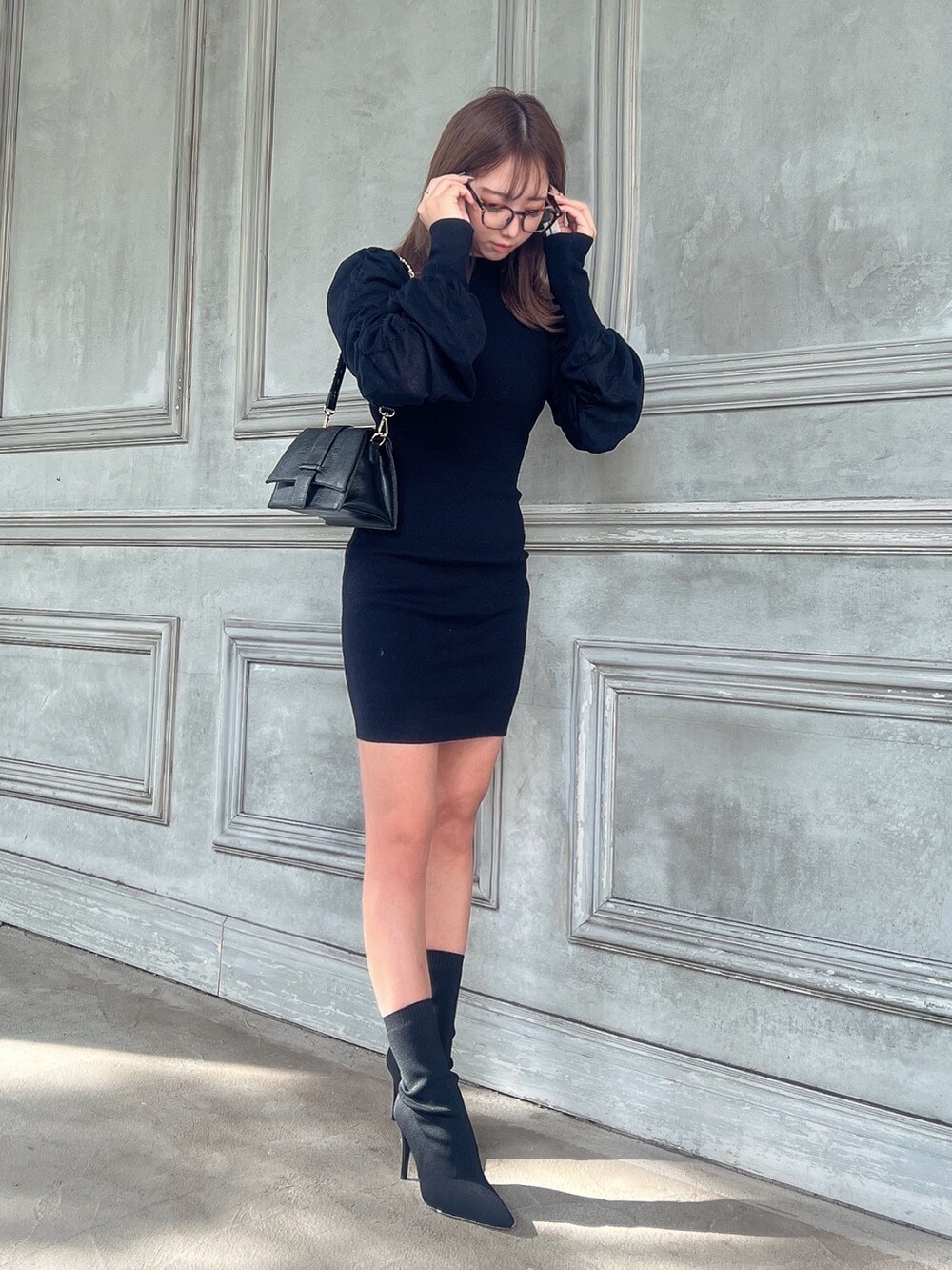 ブラック系のワンピース、ブラック系のハンドバッグ、ブラック系のブーツを着用したレディースの秋コーディネートの4枚目の写真