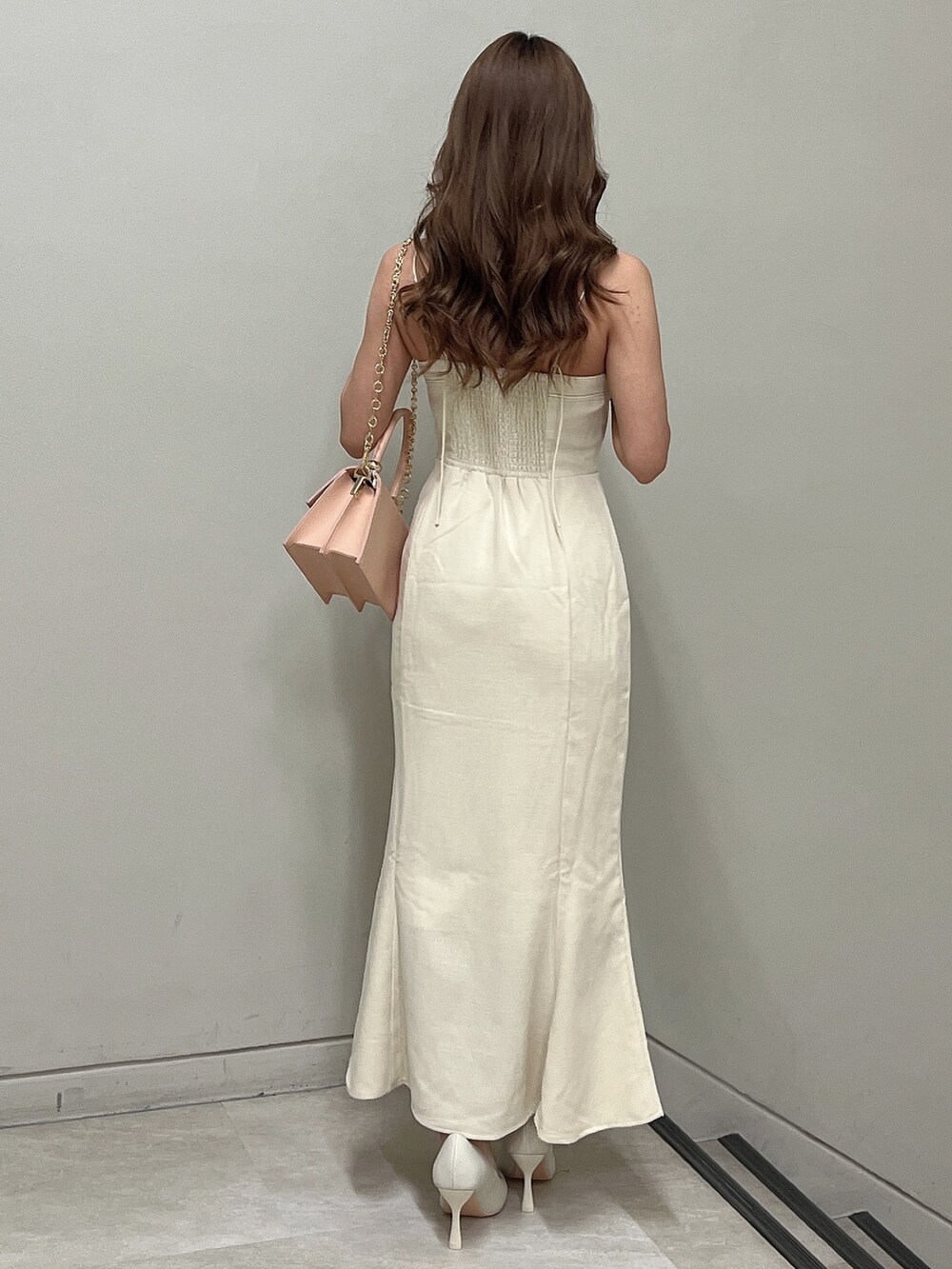 ホワイト系のパンプス、ホワイト系のワンピース、ピンク系のハンドバッグを着用したレディースの春コーディネートの3枚目の写真