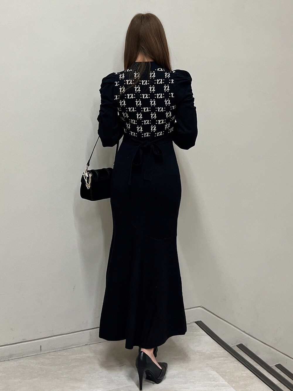 ブラック系のワンピース、ブラック系のショルダーバッグ、ブラック系のパンプスを着用したレディースの冬コーディネートの2枚目の写真