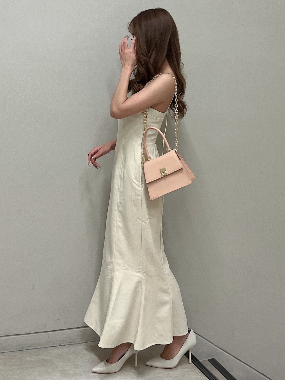 ホワイト系のパンプス、ホワイト系のワンピース、ピンク系のハンドバッグを着用したレディースの春コーディネートの2枚目の写真