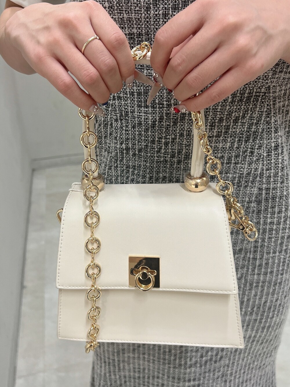 ブラック系のワンピース、ホワイト系のハンドバッグ、ホワイト系のサンダルを着用したレディースの春コーディネートの7枚目の写真