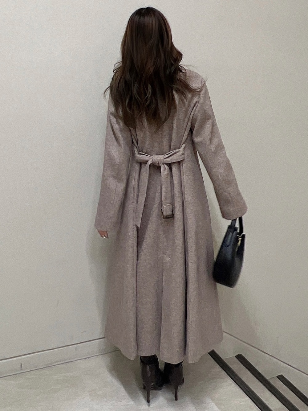 ブラウン系のチェスターコート、ブラウン系のブーツ、ブラック系のニット/セーターを着用したレディースの冬コーディネートの3枚目の写真