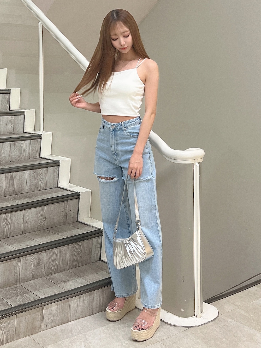 ホワイト系のキャミソール、ブルー系のデニムパンツ、シルバー系のハンドバッグを着用したレディースの春コーディネートの2枚目の写真