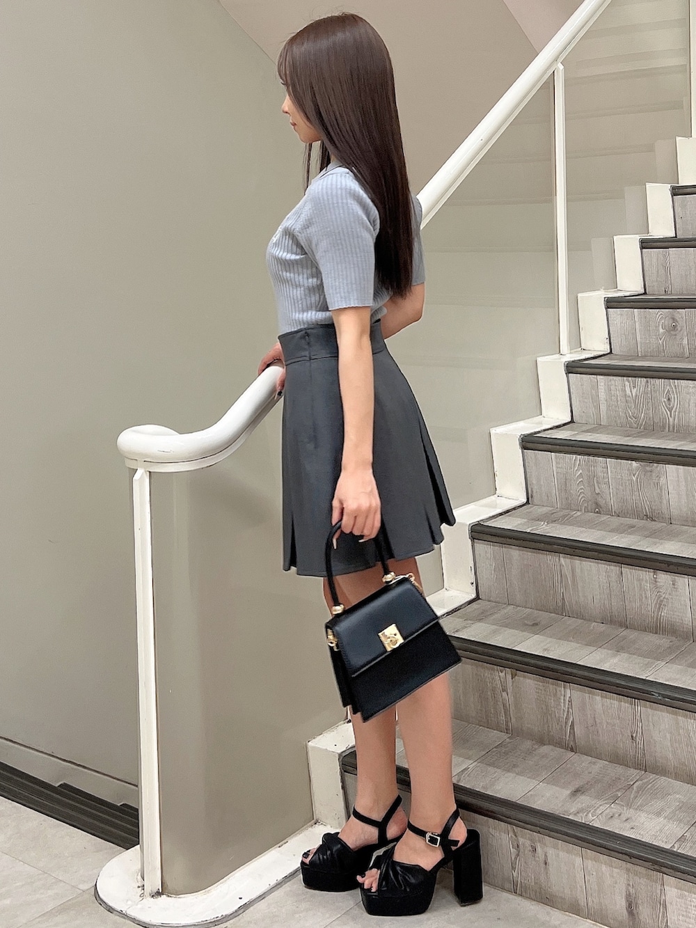 ブルー系のニット/セーター、グレー系のスカート、ブラック系のハンドバッグを着用したレディースの春コーディネートの3枚目の写真