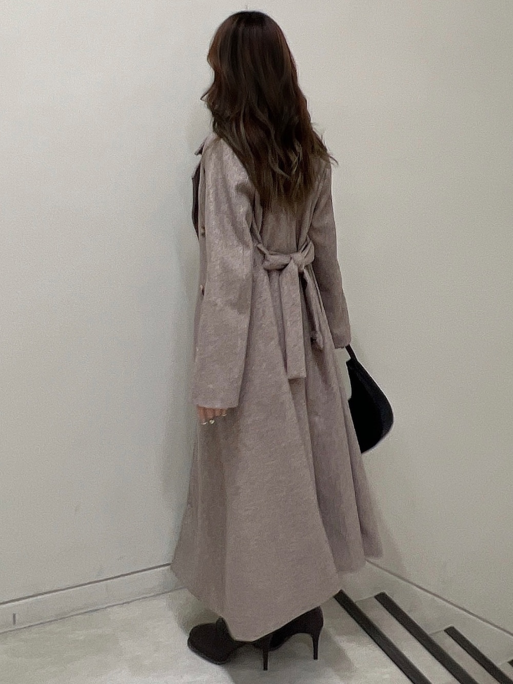 ブラウン系のチェスターコート、ブラウン系のブーツ、ブラック系のニット/セーターを着用したレディースの冬コーディネートの4枚目の写真