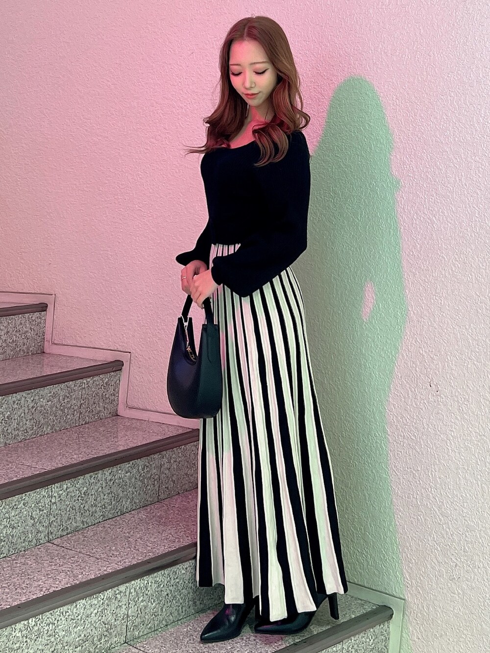 ブラック系のワンピース、ブラック系のハンドバッグ、ブラック系のブーツを着用したレディースの冬コーディネートの2枚目の写真