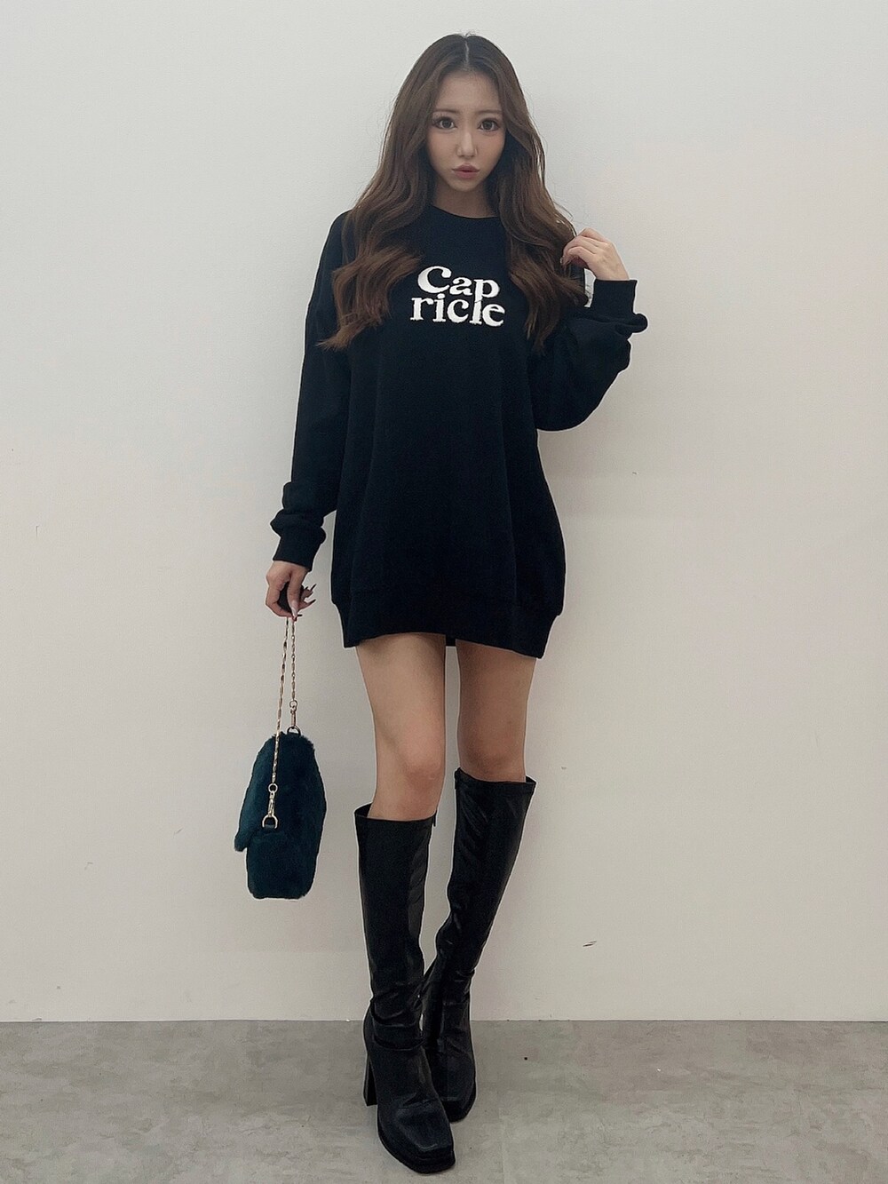 ブラック系のスウェット、グリーン系のハンドバッグ、ブラック系のブーツを着用したレディースの夏コーディネートの2枚目の写真