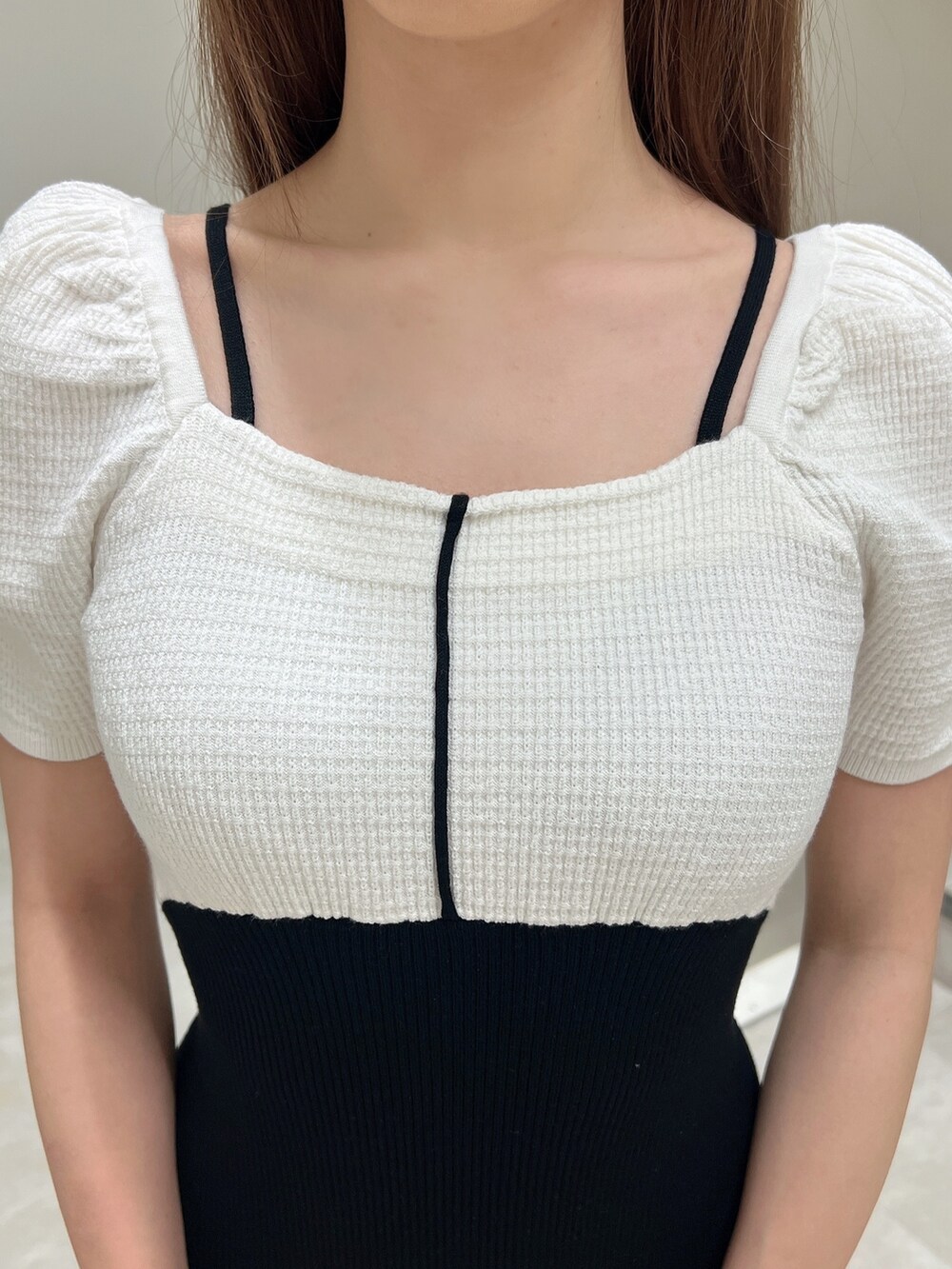 ブラック系のハンドバッグ、ホワイト系のワンピース、ブラック系のパンプスを着用したレディースの春コーディネートの5枚目の写真