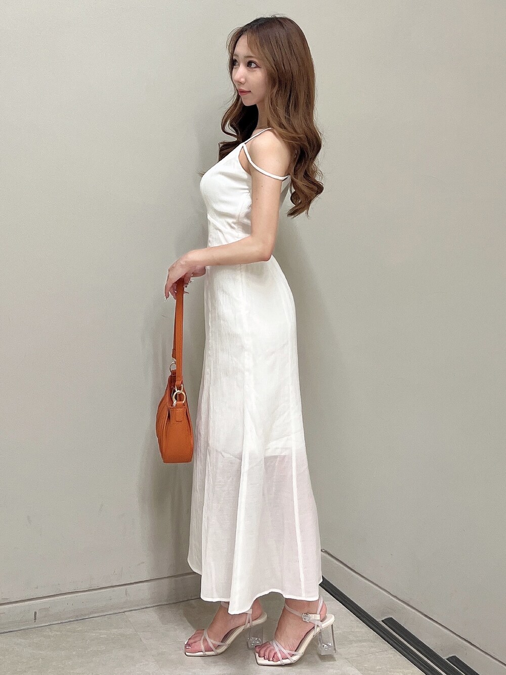 ホワイト系のワンピース、ホワイト系のサンダル、オレンジ系のハンドバッグを着用したレディースの夏コーディネートの2枚目の写真