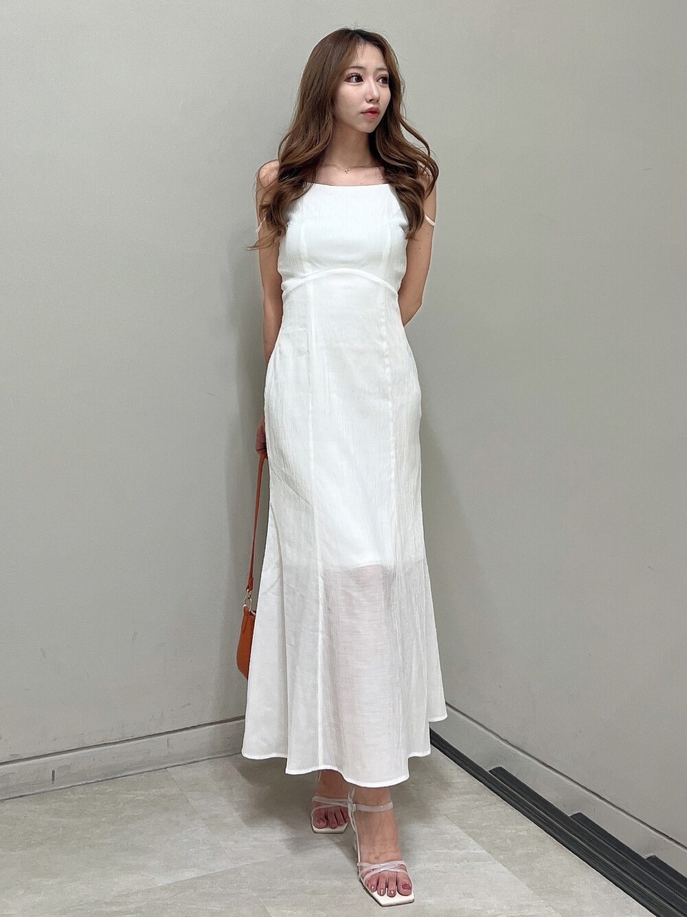 ホワイト系のワンピース、ホワイト系のサンダル、オレンジ系のハンドバッグを着用したレディースの夏コーディネートの3枚目の写真