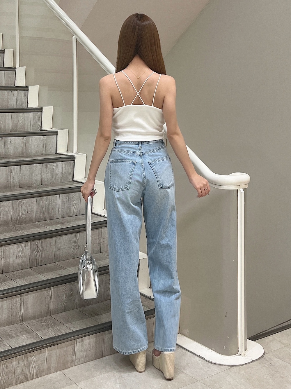 ホワイト系のキャミソール、ブルー系のデニムパンツ、シルバー系のハンドバッグを着用したレディースの春コーディネートの5枚目の写真