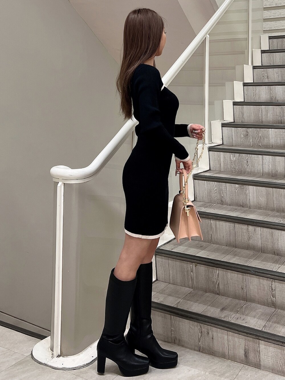 ブラック系のワンピース、ブラック系のブーツ、ピンク系のハンドバッグを着用したレディースの冬コーディネートの4枚目の写真