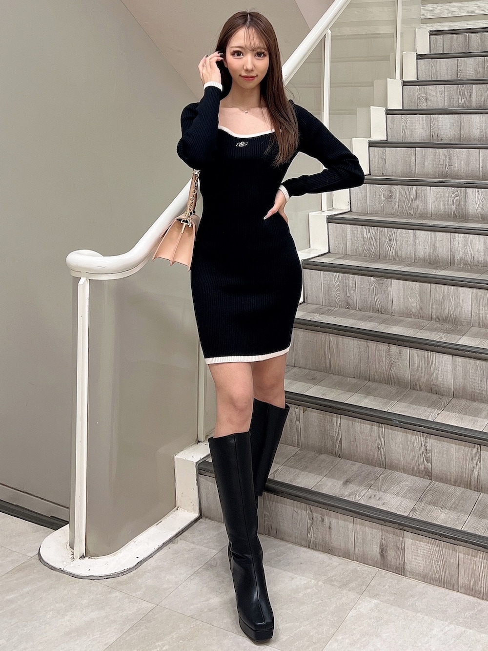 ブラック系のワンピース、ブラック系のブーツ、ピンク系のハンドバッグを着用したレディースの冬コーディネートの3枚目の写真