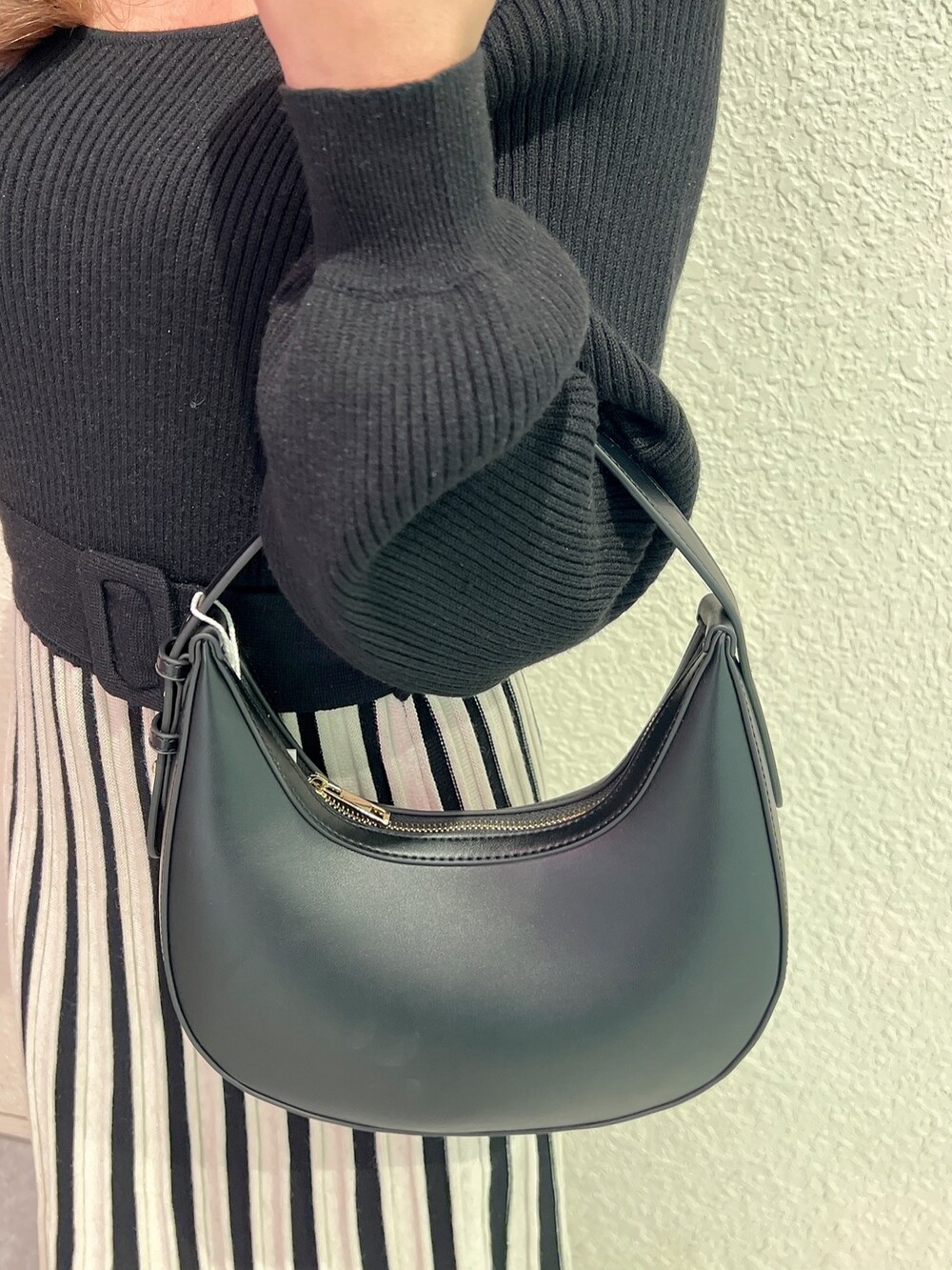 ブラック系のワンピース、ブラック系のハンドバッグ、ブラック系のブーツを着用したレディースの冬コーディネートの5枚目の写真