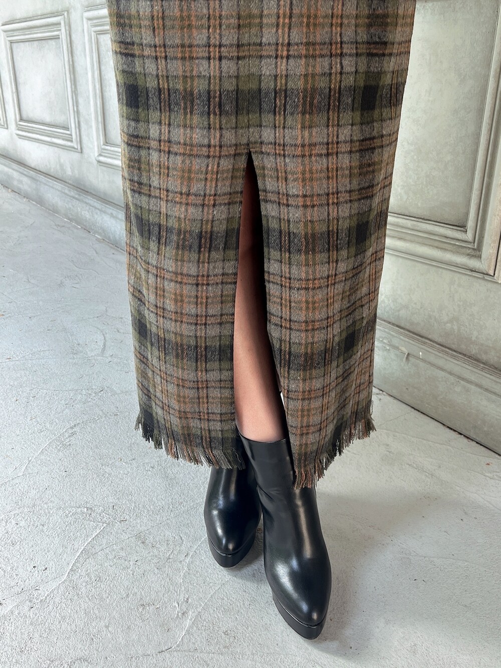 ブラック系のニット/セーター、グリーン系のスカート、ブラック系のショルダーバッグを着用したレディースの秋コーディネートの4枚目の写真