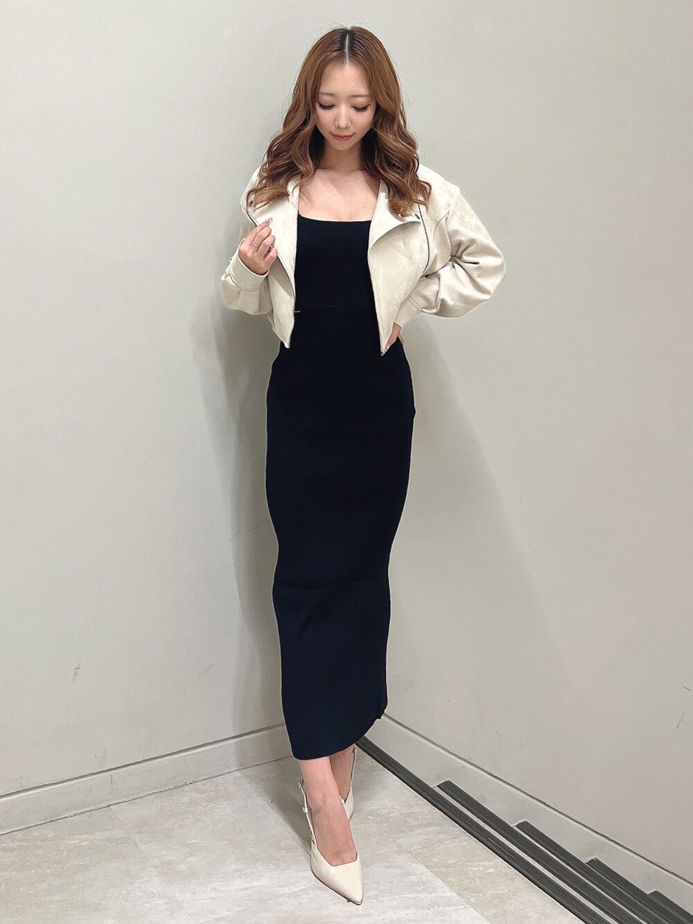 ベージュ系のライダースジャケット、ブラック系のワンピース、ベージュ系のサンダルを着用したレディースの秋コーディネートの2枚目の写真