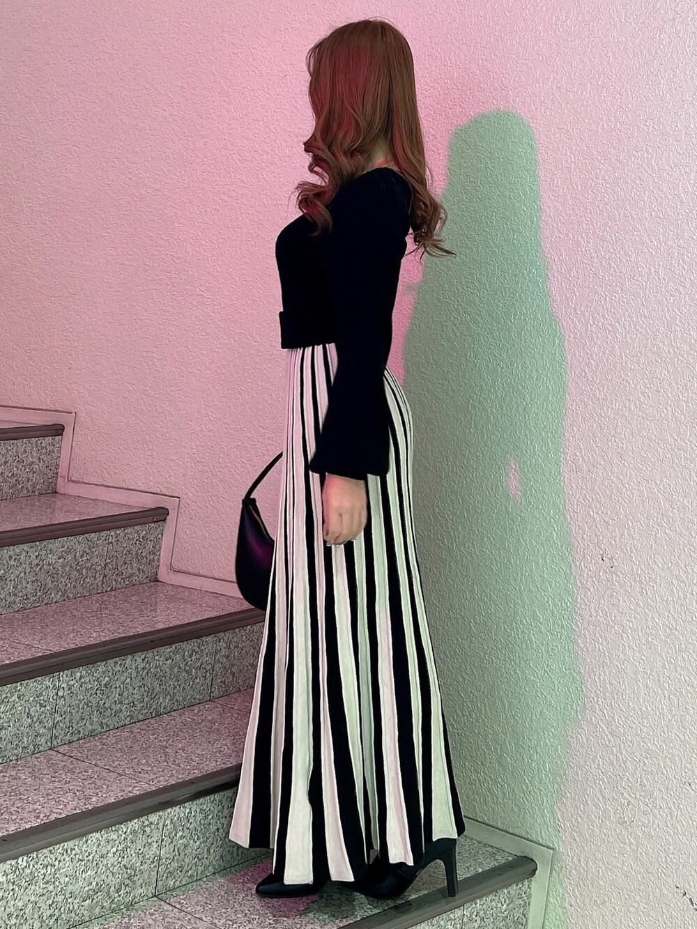 ブラック系のワンピース、ブラック系のハンドバッグ、ブラック系のブーツを着用したレディースの冬コーディネートの3枚目の写真