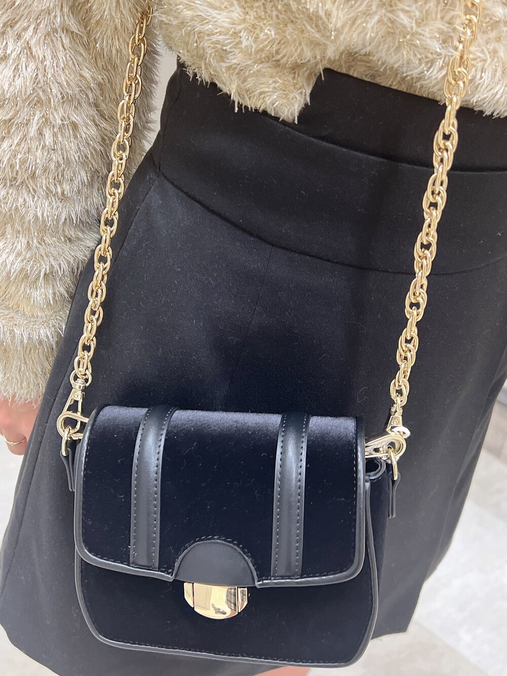 ブラック系のショルダーバッグ、ブラック系のブーツ、ベージュ系のニット/セーターを着用したレディースの冬コーディネートの4枚目の写真