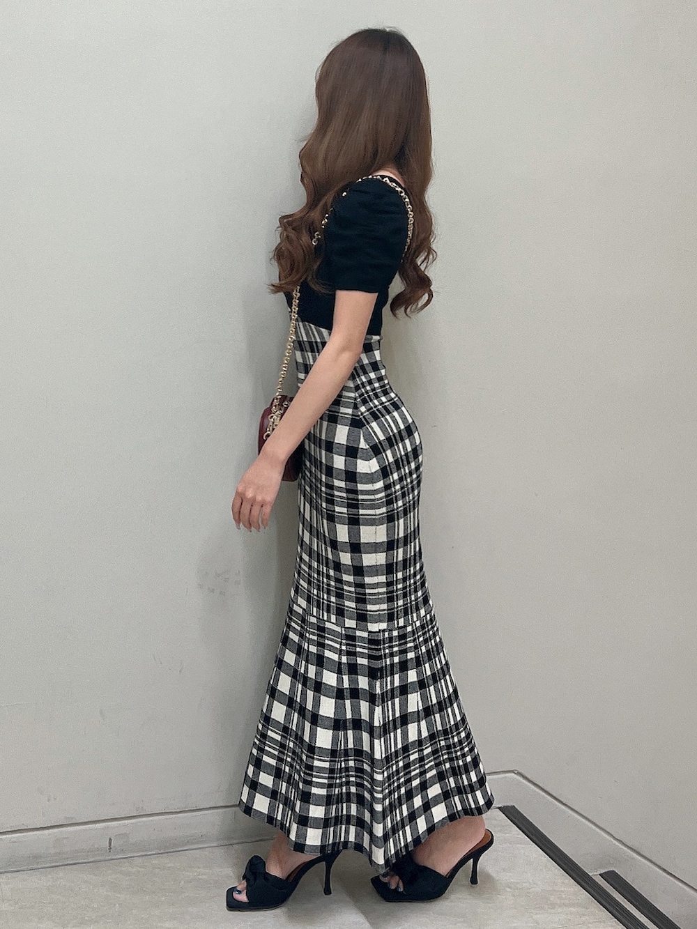 レッド系のショルダーバッグ、ブラック系のワンピース、ブラック系のサンダルを着用したレディースの夏コーディネートの3枚目の写真