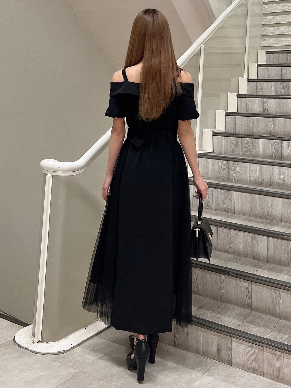 ブラック系のハンドバッグ、ブラック系のワンピース、ブラック系のパンプスを着用したレディースの春コーディネートの3枚目の写真