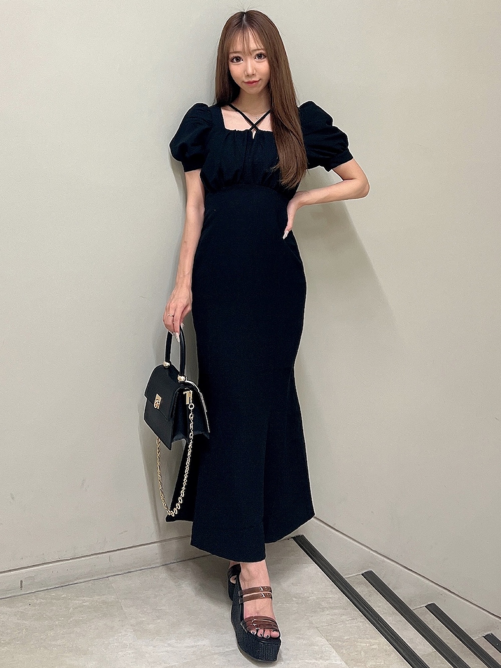 ブラック系のワンピース、ブラック系のサンダル、ブラック系のハンドバッグを着用したレディースの春コーディネートの2枚目の写真