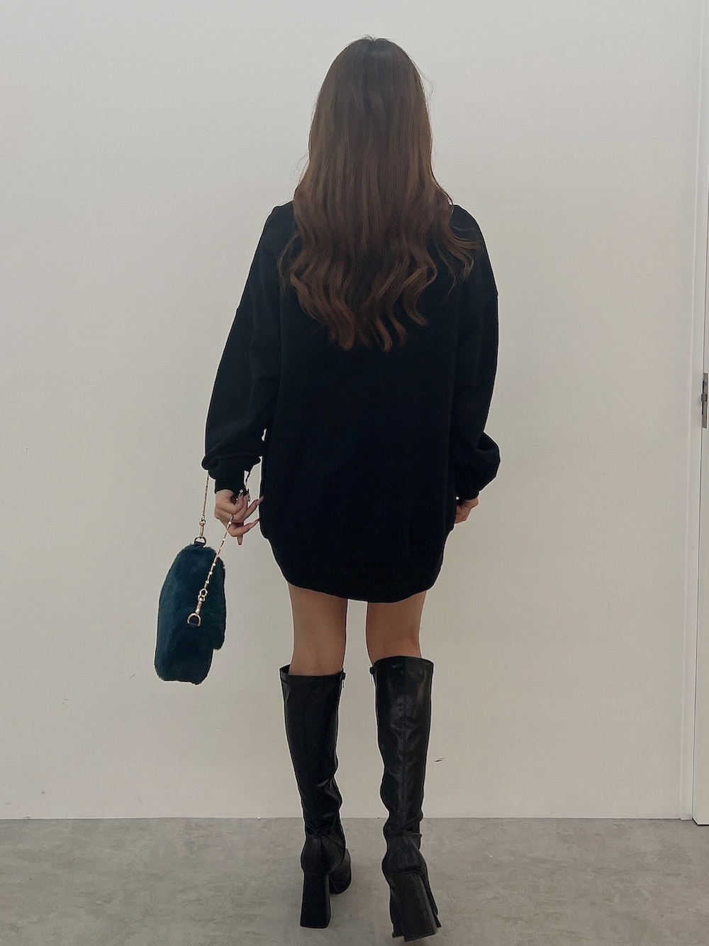 ブラック系のスウェット、グリーン系のハンドバッグ、ブラック系のブーツを着用したレディースの夏コーディネートの4枚目の写真