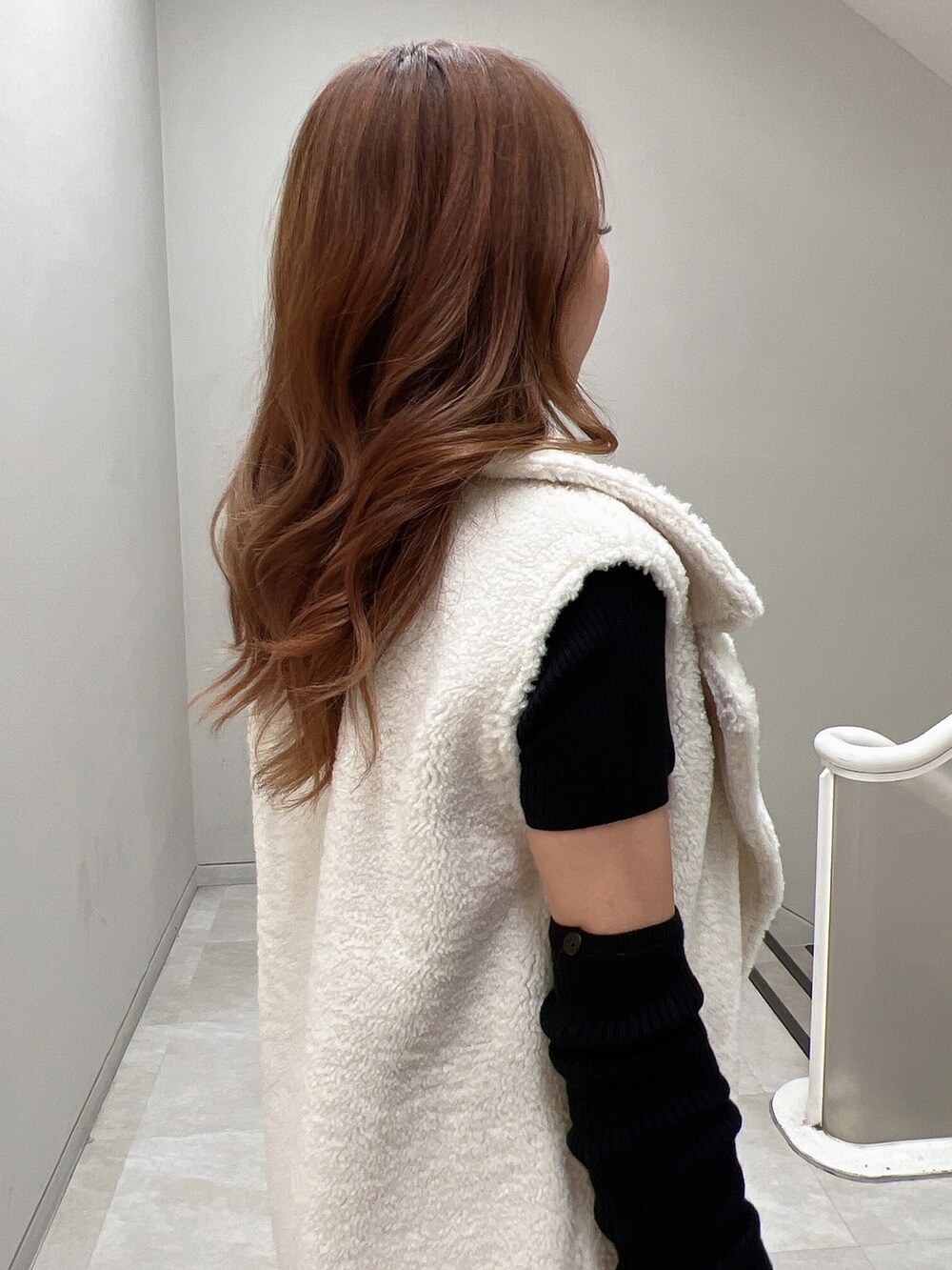 ブラック系のニット/セーター、ホワイト系のベスト、ブラック系のブーツを着用したレディースの秋コーディネートの5枚目の写真