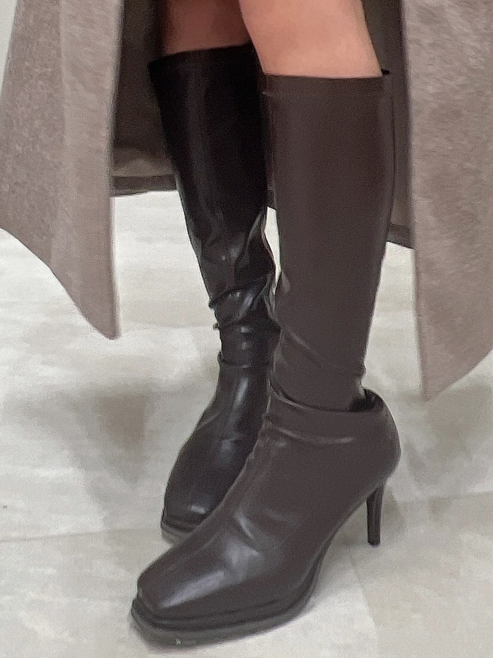 ブラウン系のチェスターコート、ブラウン系のブーツ、ブラック系のニット/セーターを着用したレディースの冬コーディネートの8枚目の写真