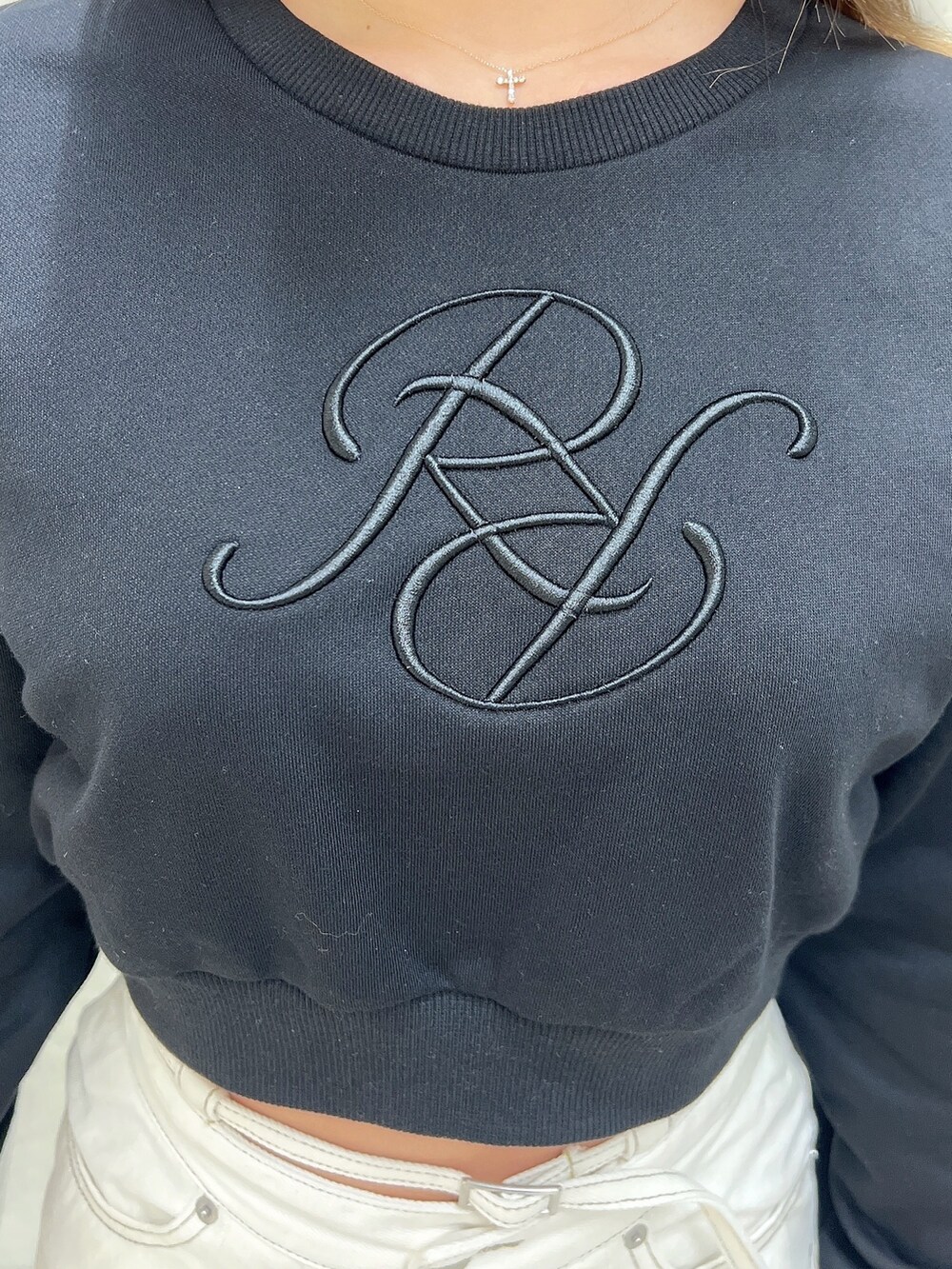 ブラック系のスウェット、ホワイト系のデニムスカート、ブラック系のパンプスを着用したレディースの冬コーディネートの5枚目の写真