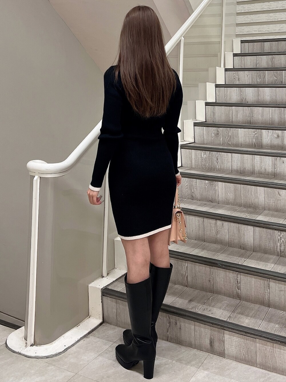 ブラック系のワンピース、ブラック系のブーツ、ピンク系のハンドバッグを着用したレディースの冬コーディネートの5枚目の写真