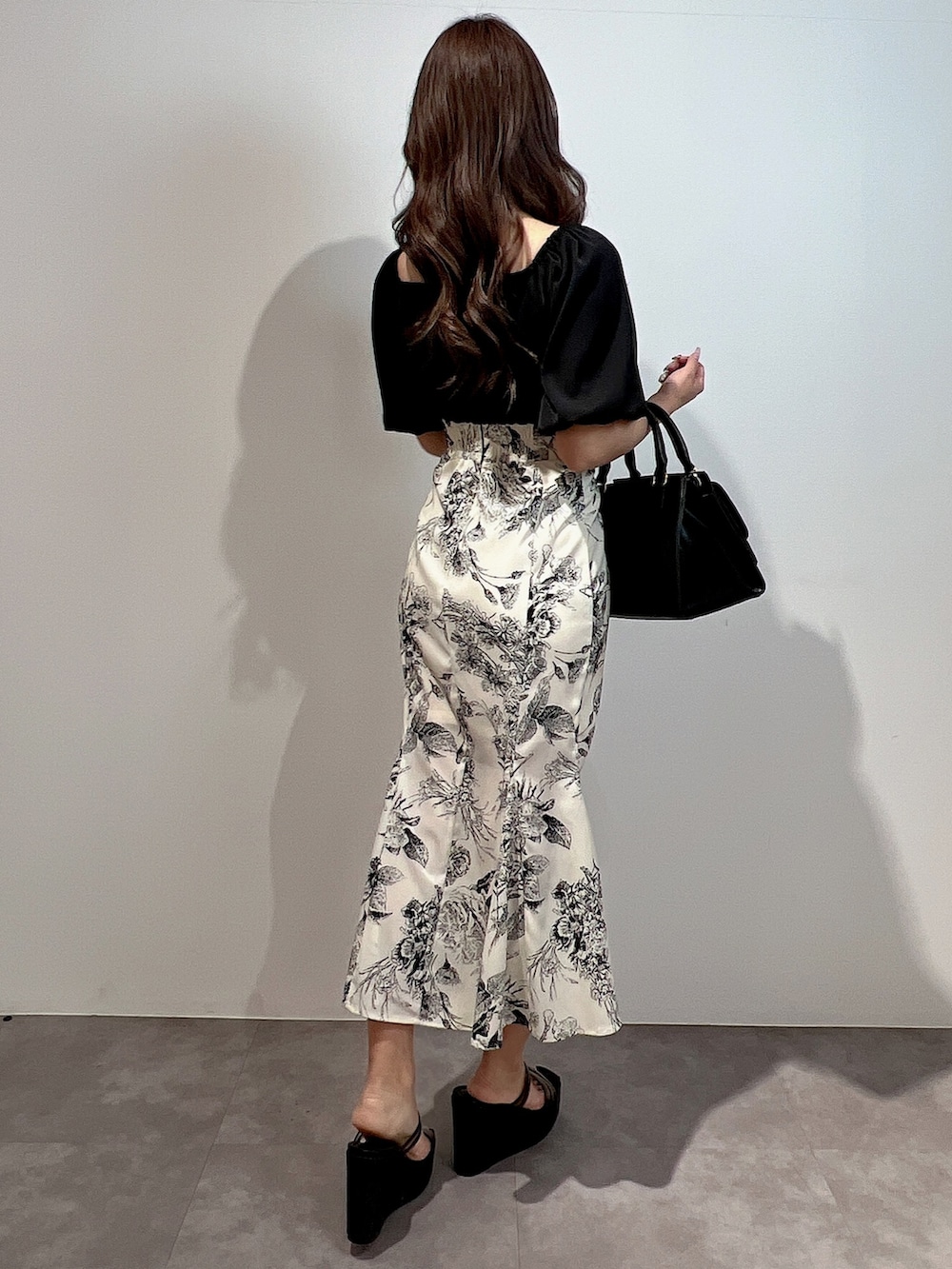 ブラック系のワンピース、ブラック系のサンダル、ブラック系のハンドバッグを着用したレディースの冬コーディネートの3枚目の写真