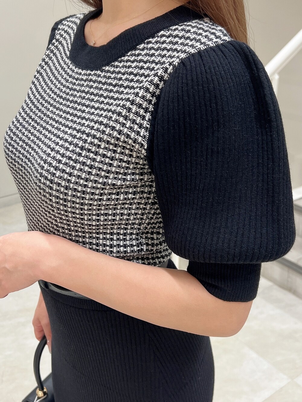 ブラック系のワンピース、ブラック系のハンドバッグ、ブラック系のパンプスを着用したレディースの春コーディネートの5枚目の写真