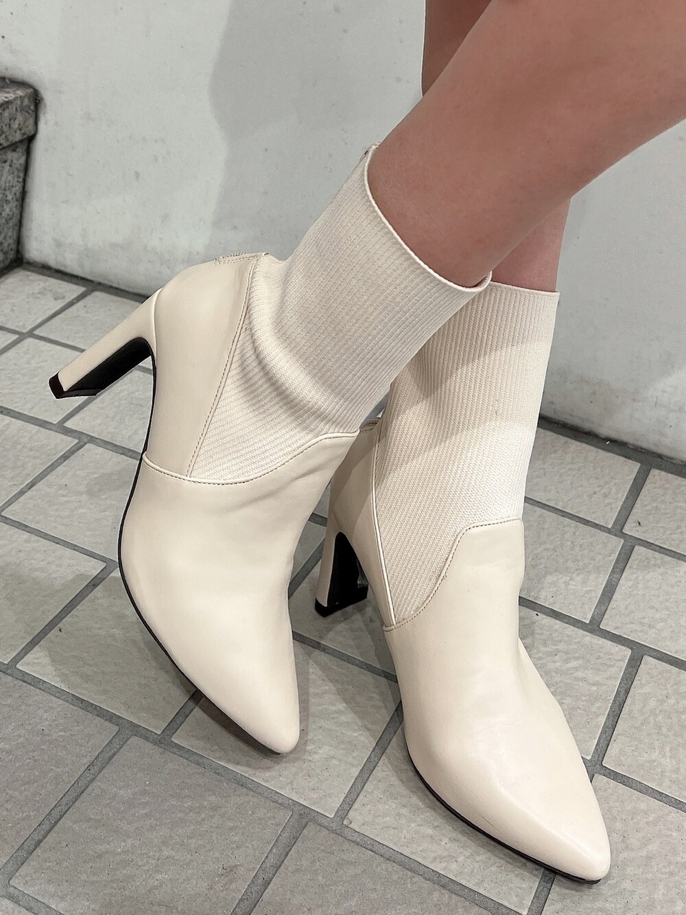 ホワイト系のライダースジャケット、ホワイト系のスカート、ブラック系のニット/セーターを着用したレディースの冬コーディネートの8枚目の写真